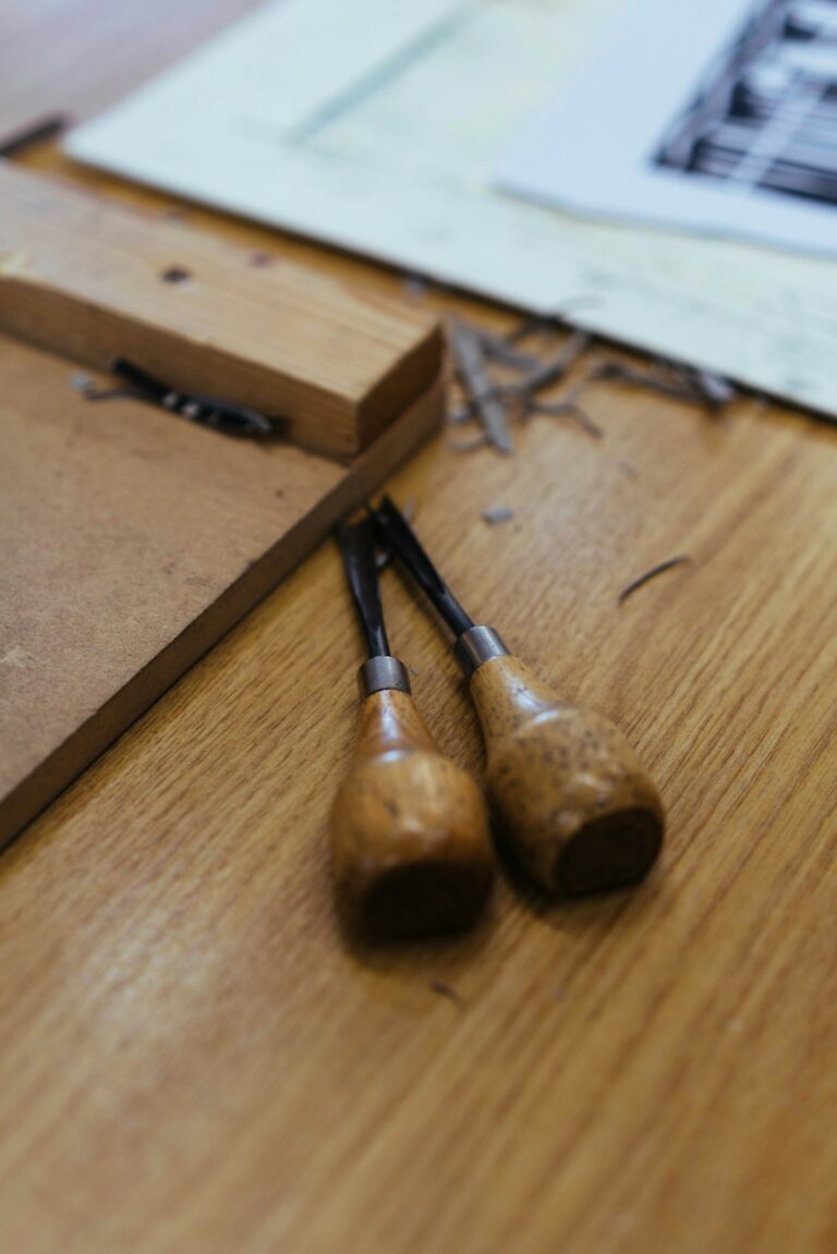 A person using a brayer to roll ink onto a carved linoleum block on a printmaking table.